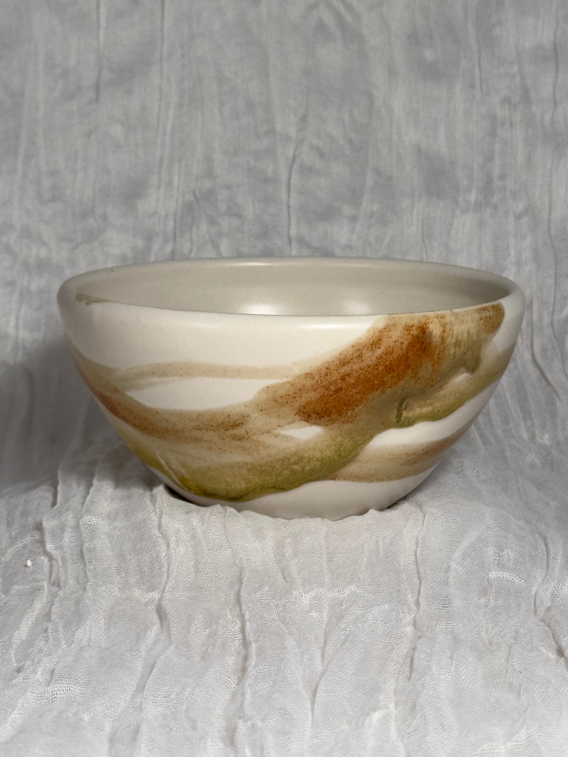 Ceramic bowl with brown and beige glaze on a gray background