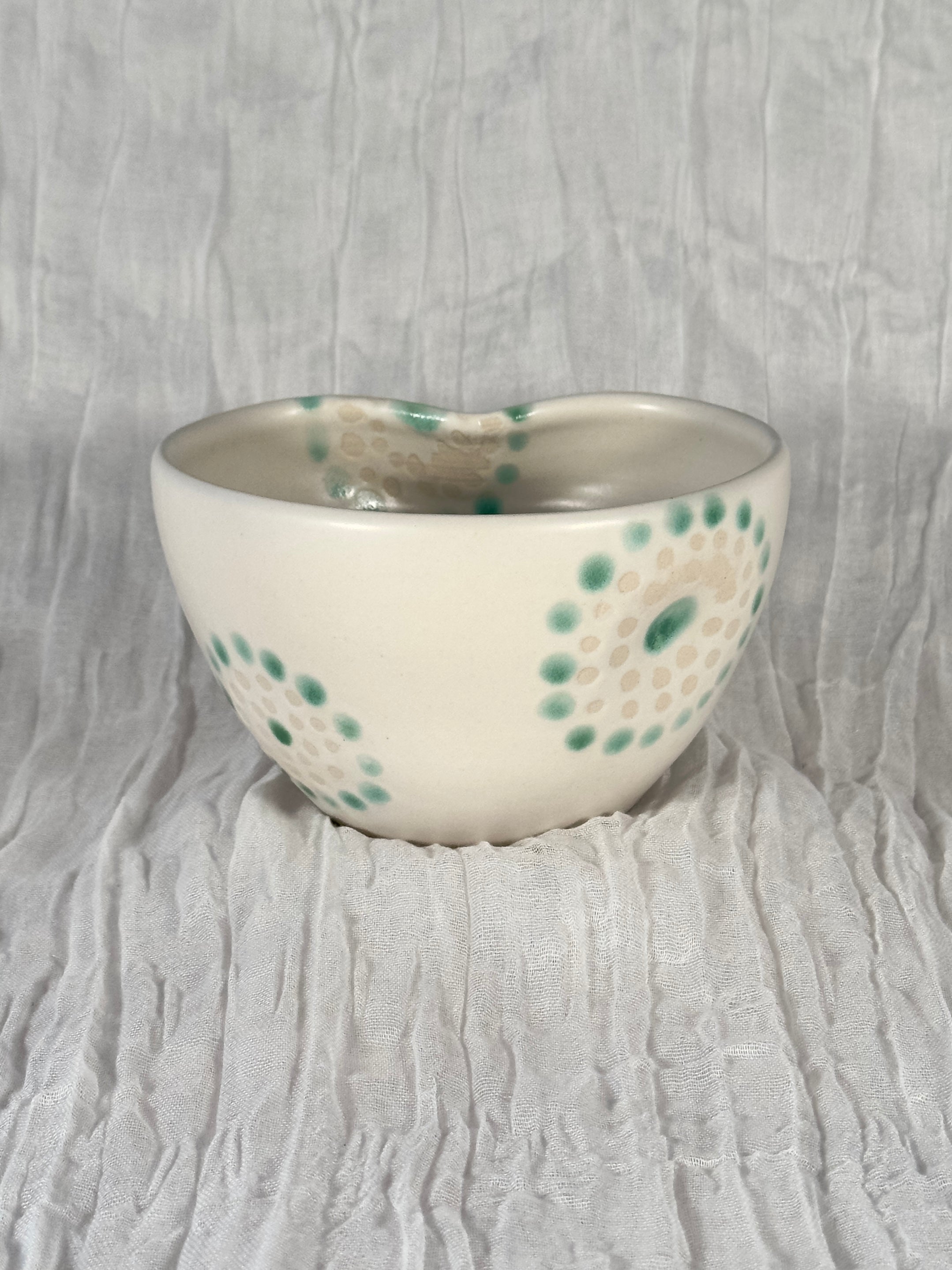 Ceramic bowl with green speckles on a textured gray background
