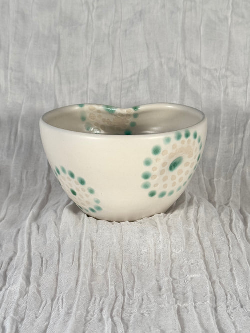 Ceramic bowl with green speckles on a textured gray background