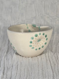 Ceramic bowl with green and beige patterns on a textured gray background