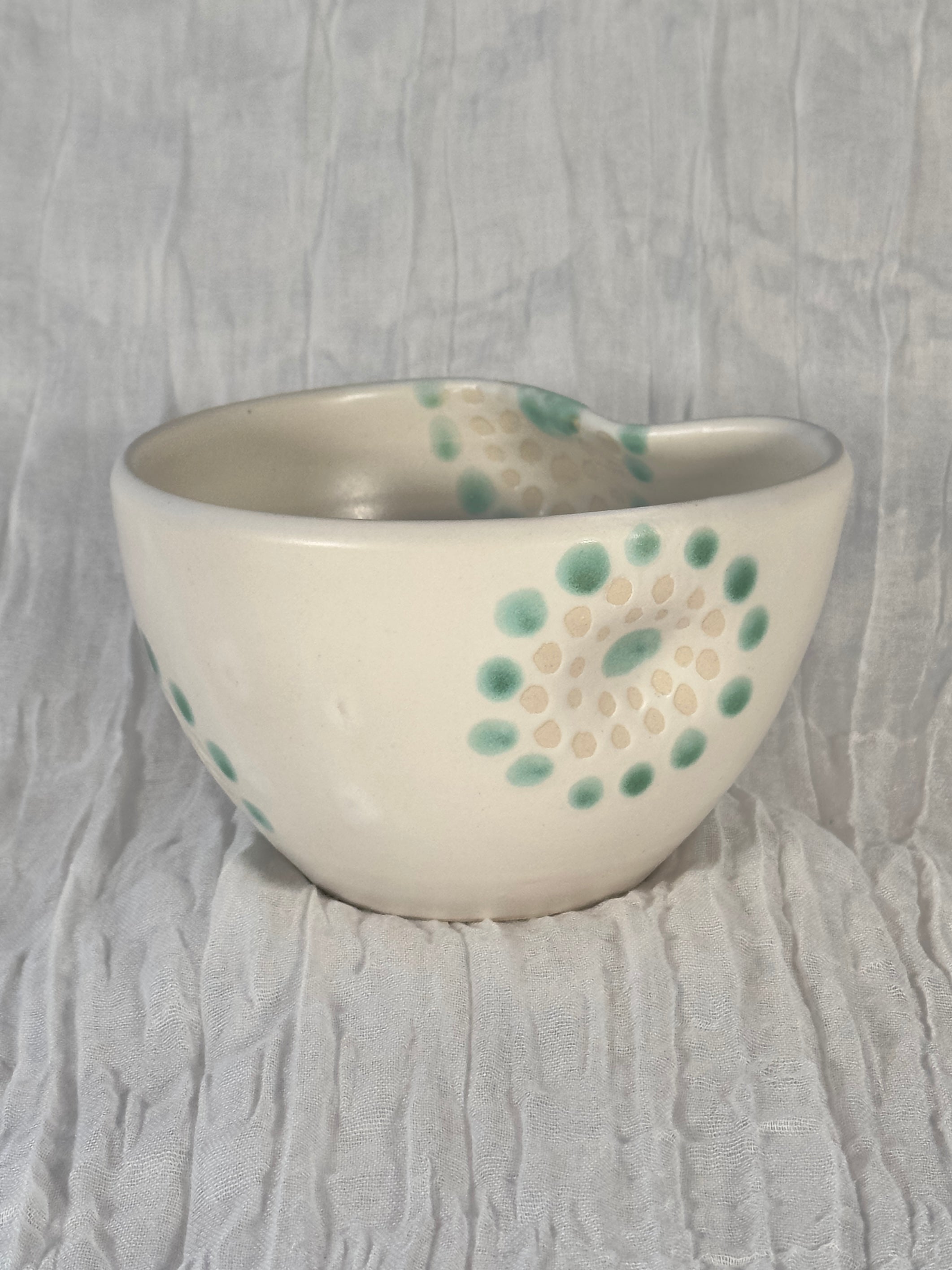 Ceramic bowl with green and beige patterns on a textured gray background