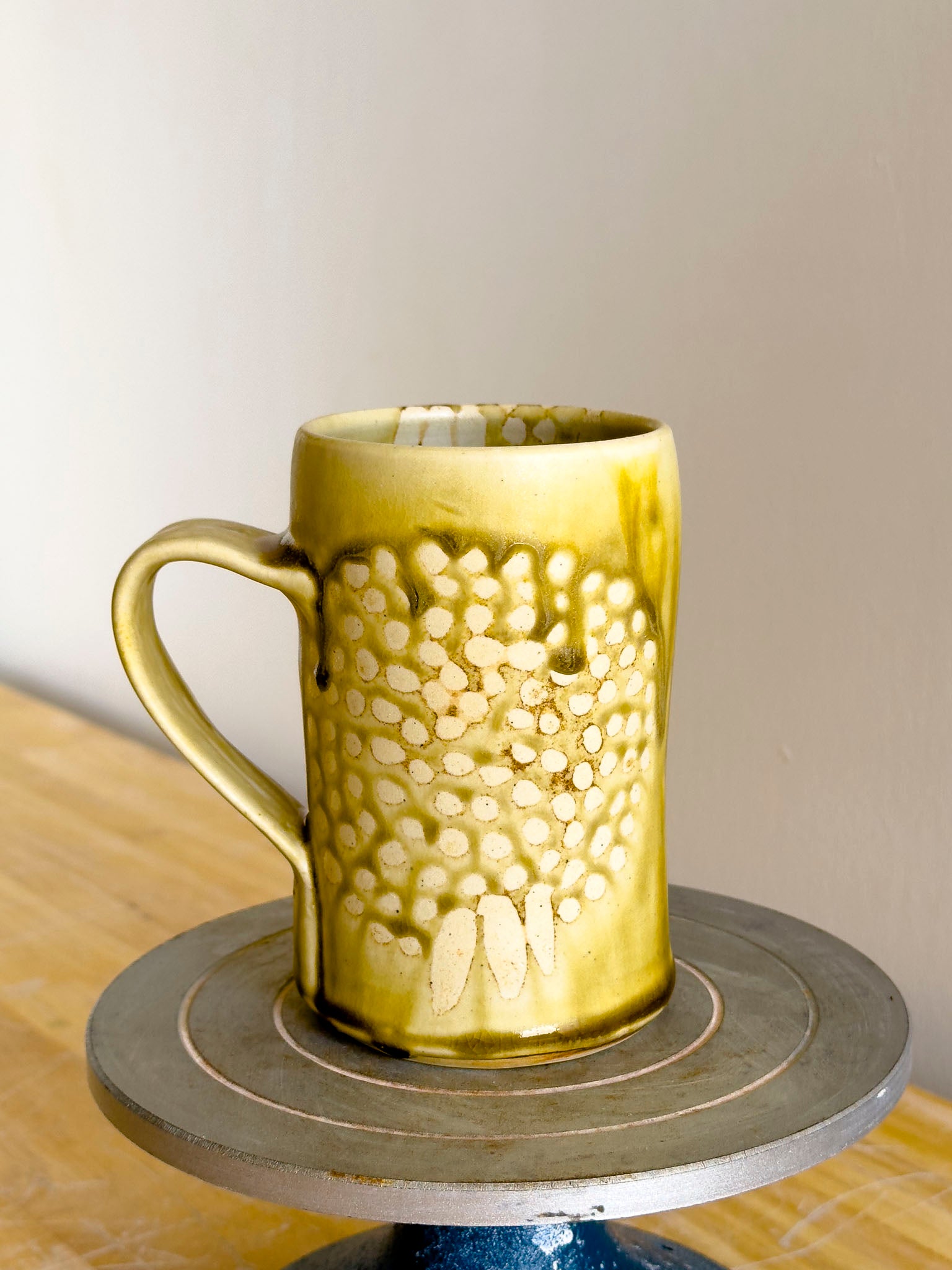 Gold textured mug on a wooden surface with a neutral background