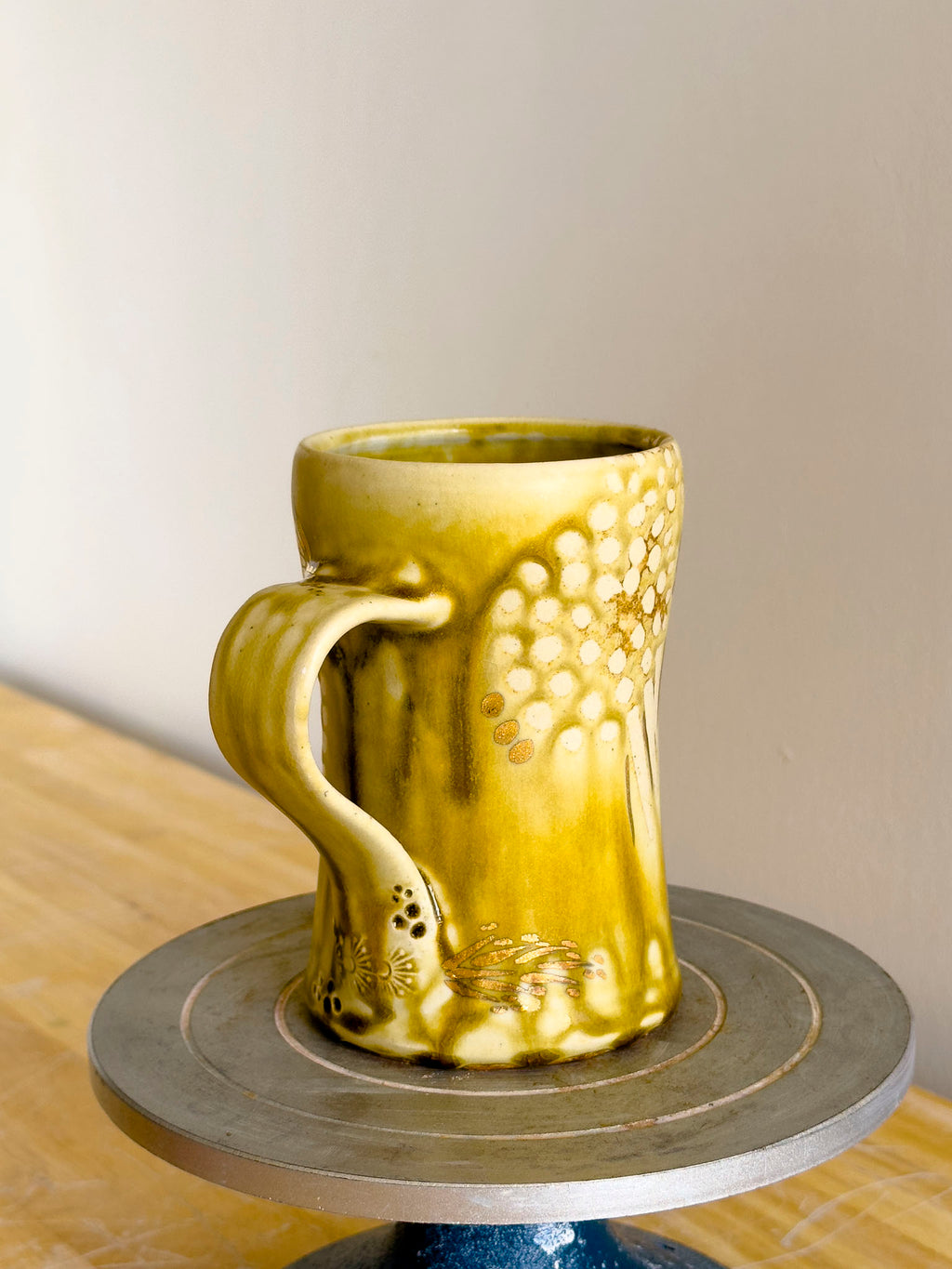 Yellow ceramic mug on a small round table with a neutral background