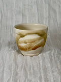 Ceramic cup with marbled design on a textured gray background
