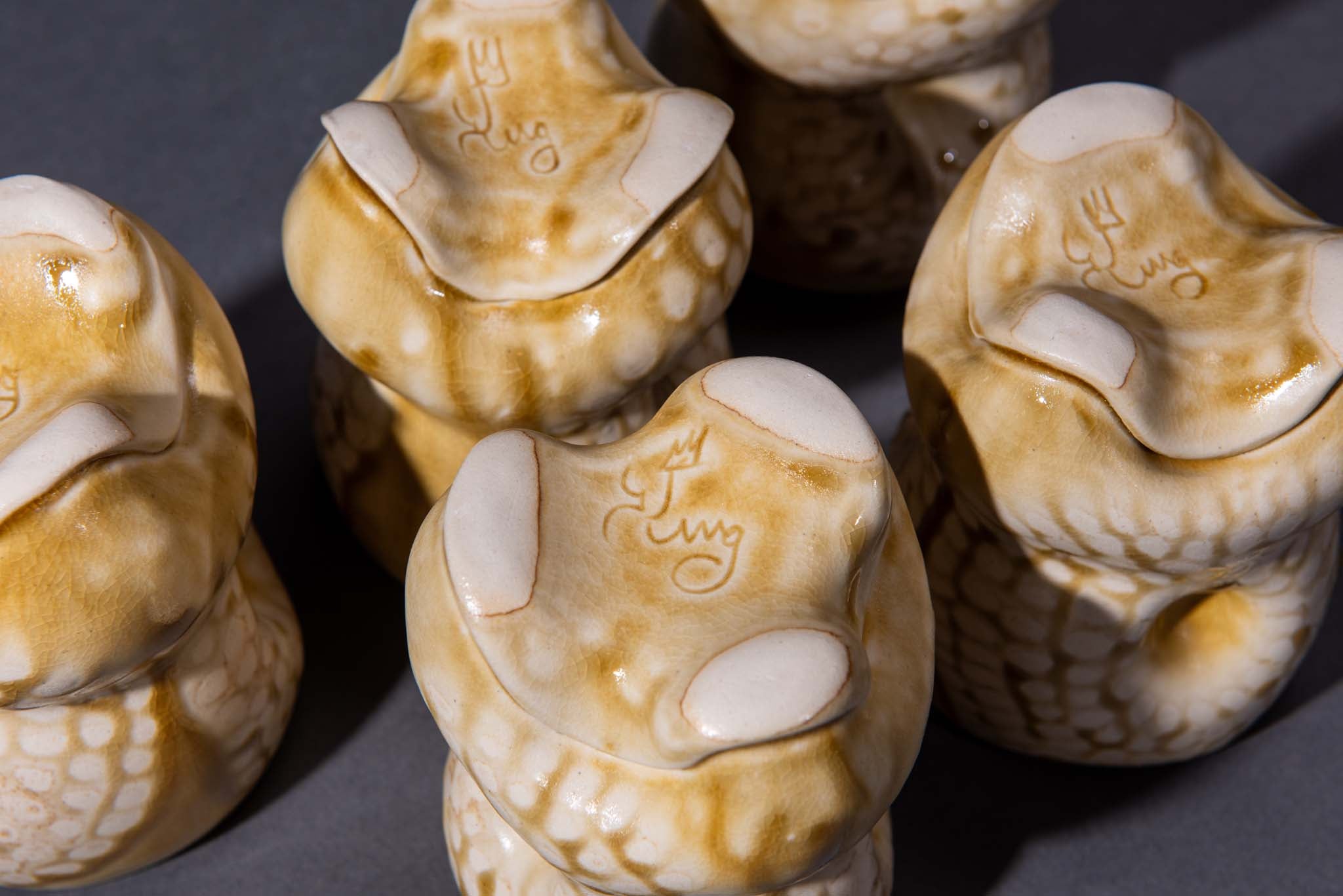 Close-up of artist signature on the bottom of handmade organic cups with a dark background