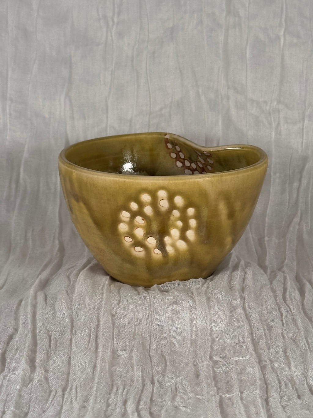 Yellow brown ceramic bowl with decorative patterns on a textured gray background