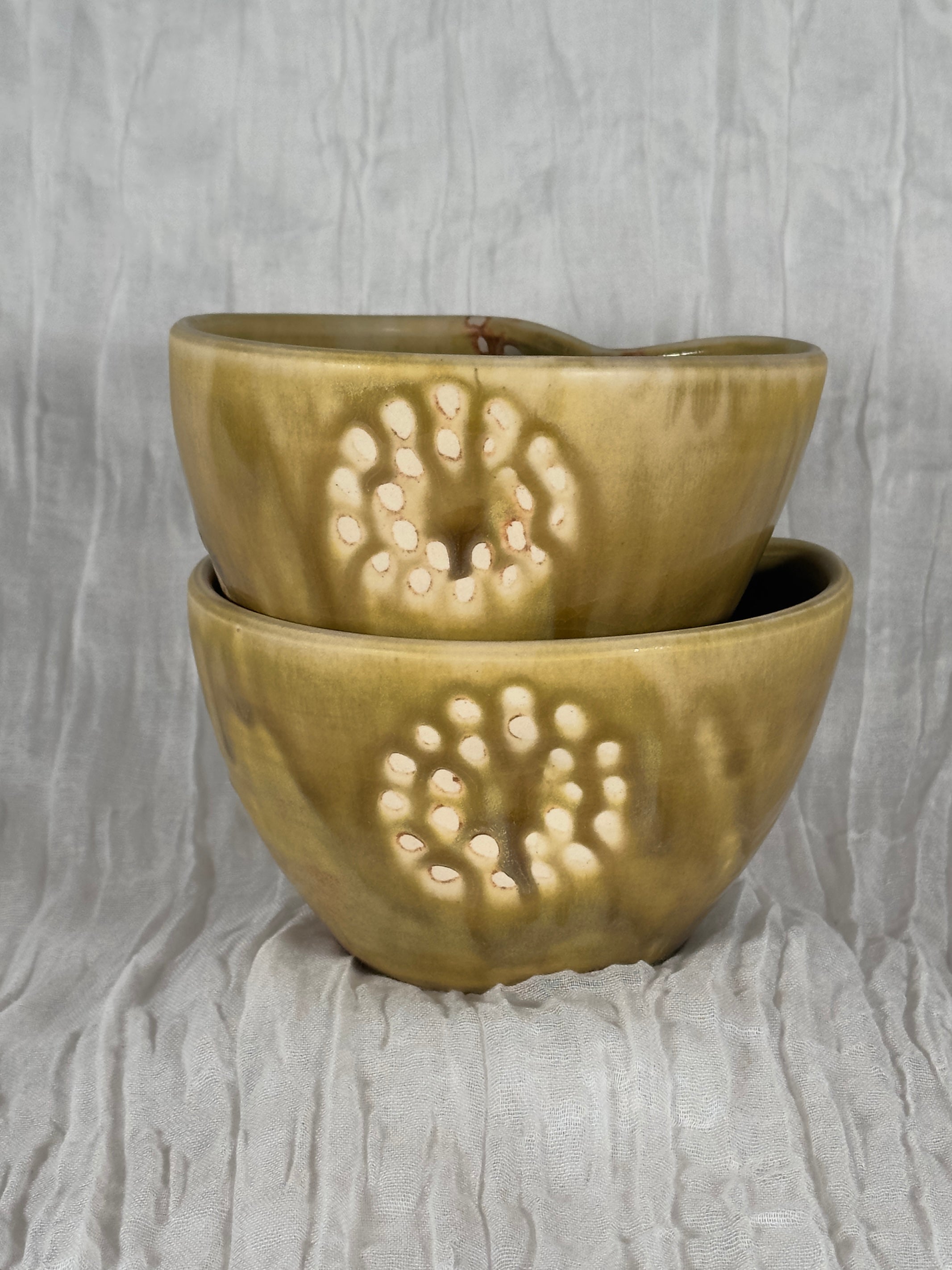 Two stacked ceramic bowls with a textured surface on a gray background
