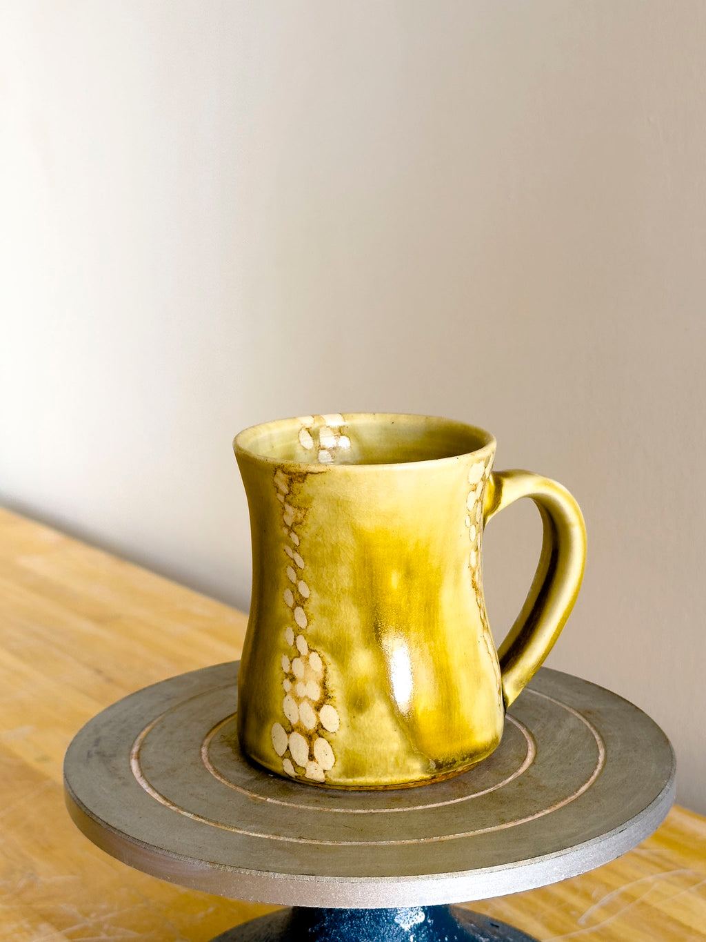 Yellow ceramic mug on a small round table with a neutral background