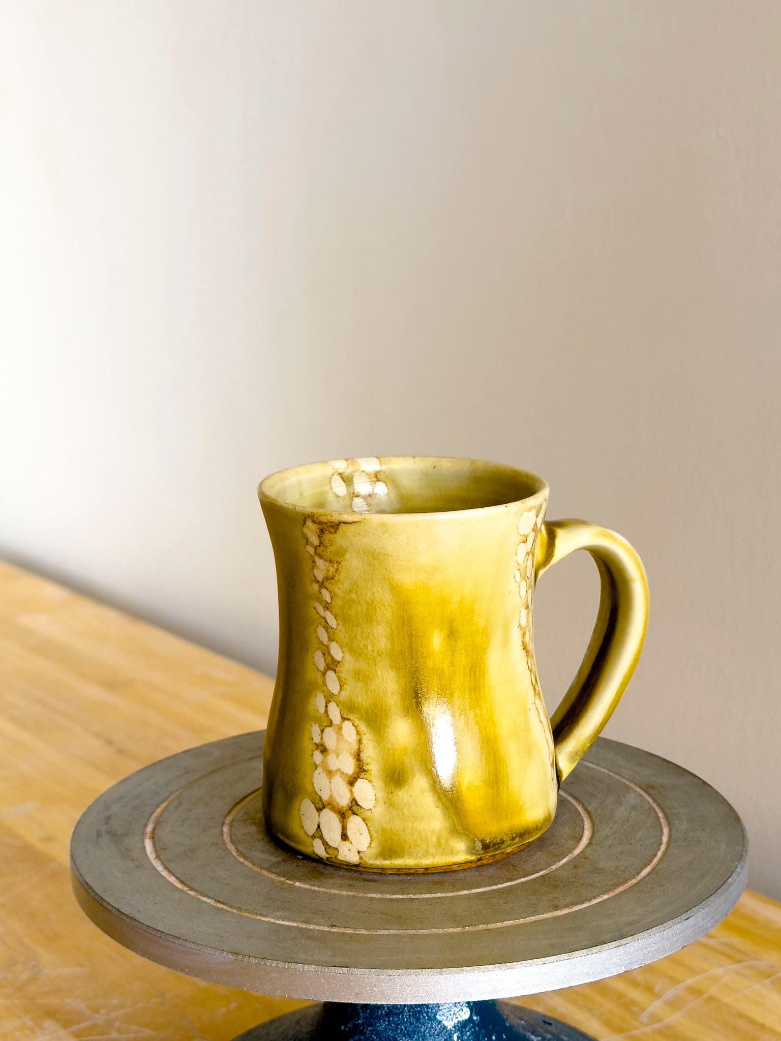 Yellow ceramic mug on a small round table with a neutral background