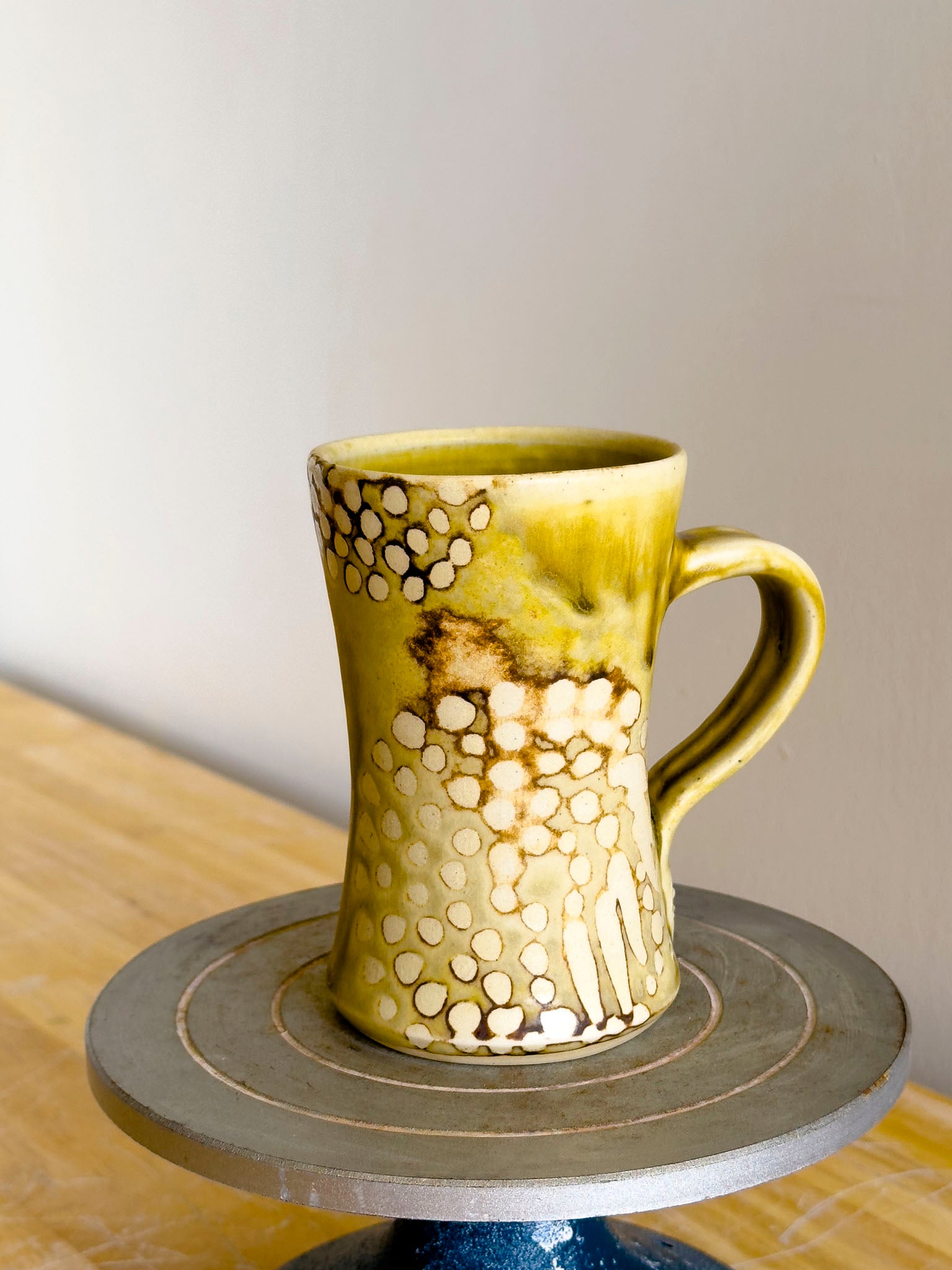 Yellow ceramic mug with decorative patterns on a wooden surface