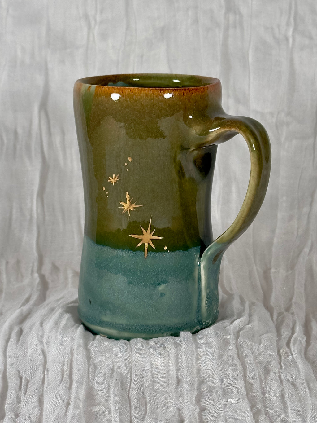Green ceramic mug with star designs on a textured white background