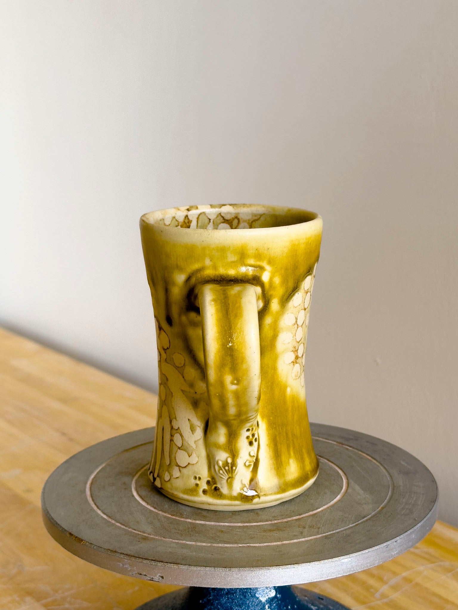 Green ceramic mug on a gray stand with a blurred background