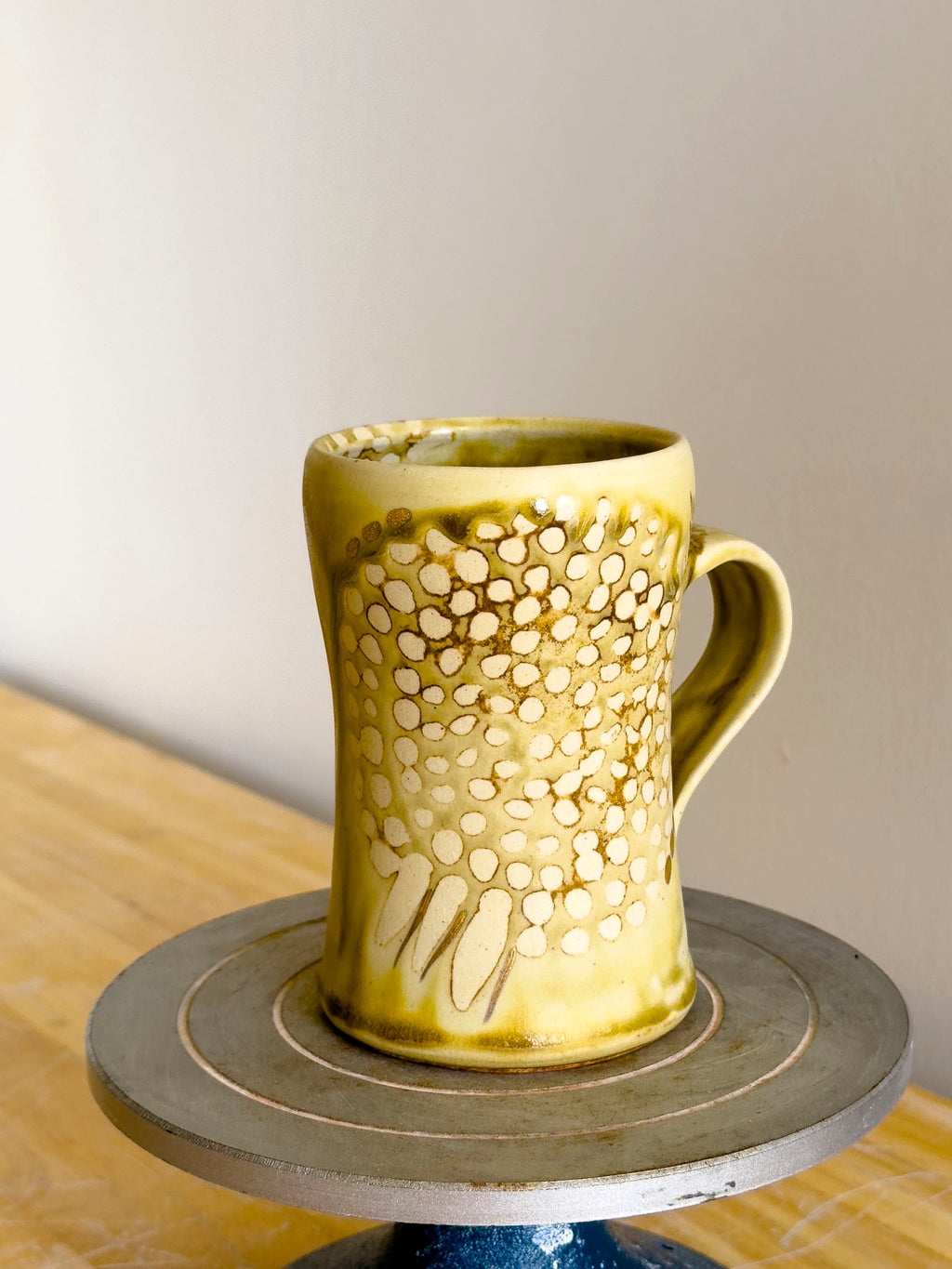 Yellow ceramic mug with decorative patterns on a wooden surface