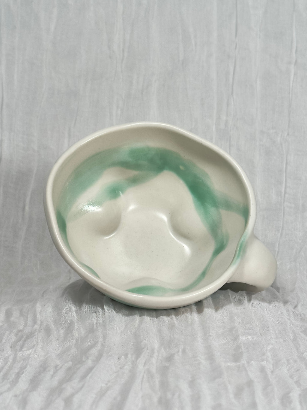 Ceramic bowl with green marbled design on a textured gray surface