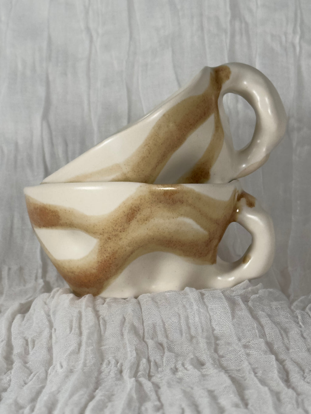 Two ceramic cups with abstract design on a textured surface